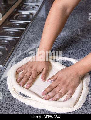 Chef préparant les mains de pâte à pizza. Pâte à pizza roulée et pétrie. Cuire les mains en pétrissant la pâte, saupoudrer un morceau de pâte avec de la farine de blé blanc Banque D'Images