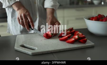 Femme emballant des fraises fraîches dans des sacs de mise sous vide pour la congélation et le stockage à long terme sur le comptoir de la cuisine. Banque D'Images