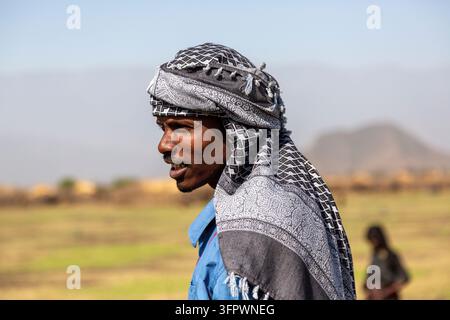 Un homme portant un foulard à carreaux noir et blanc sur une chemise bleue regarde au loin de profil, région Amhara, Artuma, Éthiopie Banque D'Images