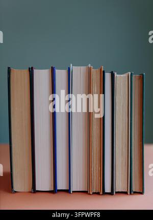 Rangeée de vieux livres reliés aux pages jaunies, équilibrés verticalement sur une étagère Banque D'Images