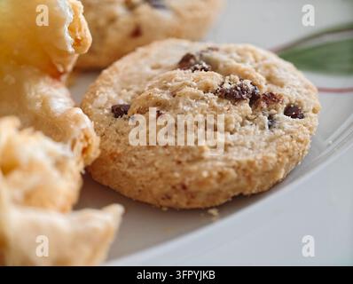 Un plan rapproché détaillé de plusieurs biscuits aux flocons d'avoine et raisins secs, mettant en évidence leur surface texturée et les raisins secs visibles. Une pâtisserie feuilletée et dorée est b Banque D'Images