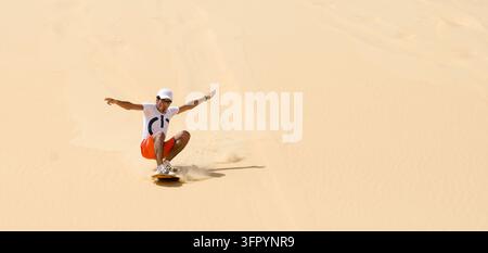 Siwa, Égypte – 26 septembre 2014 : Une personne descend sur une planche les dunes de sable en Égypte Banque D'Images
