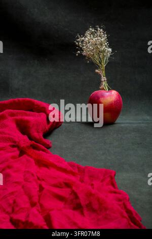 Tissu rouge et une pomme rouge avec un petit bouquet de fleurs Banque D'Images