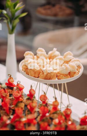 Petits choux à la crème et apéritifs à la tomate sur un buffet de catering élégant Banque D'Images