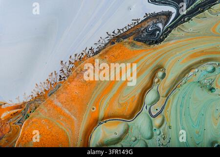 Texture abstraite d'art fluide mettant en vedette des vagues de peinture orange vif et vert menthe avec des bulles Banque D'Images