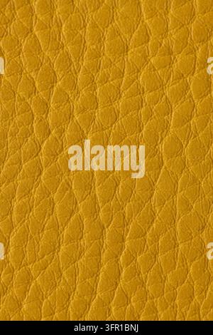 Une vue rapprochée d'une texture de cuir jaune lisse, mettant en évidence son grain fin de galet et sa finition mate douce. Banque D'Images
