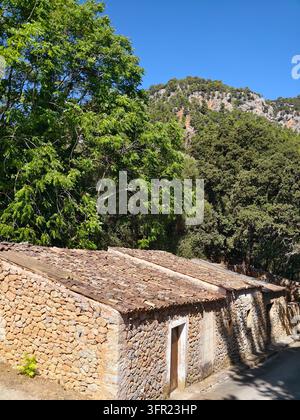 Maisons traditionnelles en pierre avec des toits en tuiles de terre cuite érodées nichées dans un paysage verdoyant. Les bâtiments présentent des murs en pierre naturelle et sim Banque D'Images