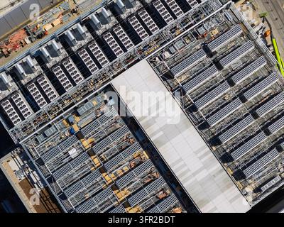 Bâtiment de centre de données industriel montrant des rangées organisées de ventilateurs de refroidissement et d'unités de matériel serveur sur le toit lors d'un après-midi ensoleillé et lumineux avec v Banque D'Images