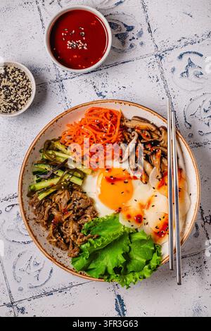 Bibimbap avec des légumes colorés, du bœuf et de l'œuf dans un bol Banque D'Images