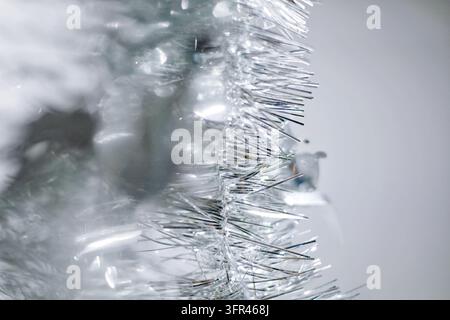 Close-up d'une guirlande en lamettes argentées avec des reflets étincelants et un flou doux. Fond de papier peint festif abstrait pour Noël, le Nouvel An, les vacances d'hiver Banque D'Images