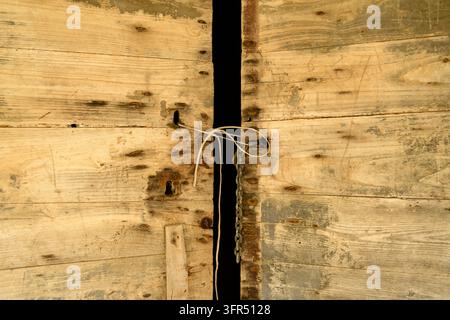 Planches en bois vieilles avec un étroit écart et une simple attache en ficelle, montrant une texture rustique usée. Banque D'Images