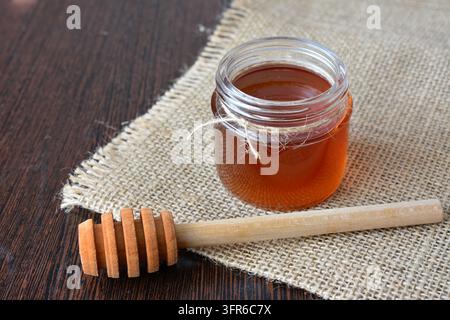 Pot de miel avec cuillère sur lin rustique avec un espace de copie rayon de soleil Banque D'Images