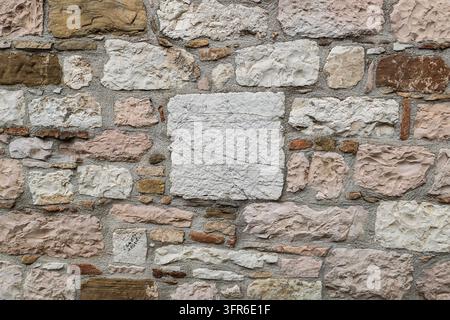 Close-up d'un mur rustique en pierres naturelles irrégulières dans des tons chauds de beige, gris et brun, Gubbio, Ombrie, Italie Banque D'Images