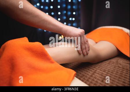 gros plan sur des mains massant le muscle du mollet d'un homme. Thérapeute appliquant une pression sur la jambe d'une femme Banque D'Images