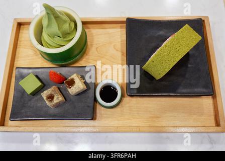 Vue aérienne d'un dessert japonais au matcha servi sur un plateau en bois à Bangkok, Thaïlande, avec une glace molle dans une tasse en bambou, un gâteau éponge à la fraise, etc. Banque D'Images