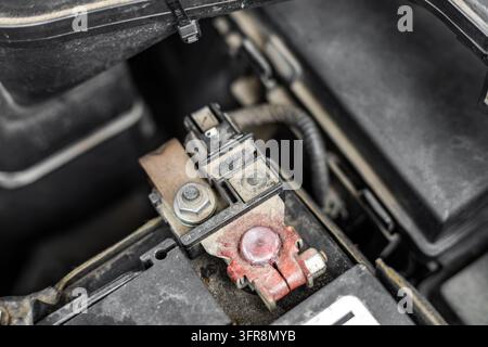 Un plan rapproché détaillé met l'accent sur une connexion de borne de batterie de voiture, un câble de conduction et un boîtier de fusibles dans le compartiment moteur. La technica Banque D'Images
