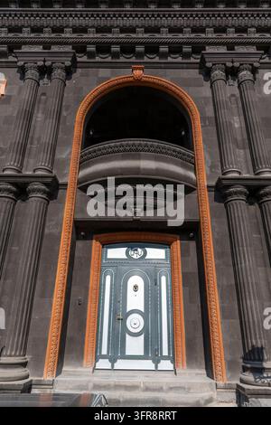 Façade ornée en pierre noire avec un balcon arqué sculpté et une porte, province de Shirak, Gyumri, Arménie Banque D'Images