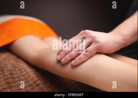 Mains masculines massant le muscle du mollet humain. Thérapeute appliquant une pression sur la jambe d'une femme Banque D'Images