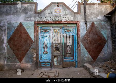 Porte en bois bleu patiné avec une inscription gujarati et un chat dormant par terre à proximité, Gujarat, Mandvi, Inde Banque D'Images