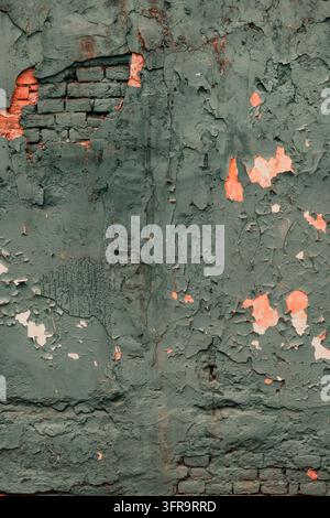 Mur érodé avec un enduit gris-vert fissuré, de la peinture écaillée et de la brique rouge apparente. Texture architecturale usée idéale pour les arrière-plans grunge Banque D'Images