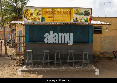 Un stand de bar routier vide avec des tabourets en bois est fermé sous un toit en tôle ondulée, Région Maritime, Lomé, Togo Banque D'Images