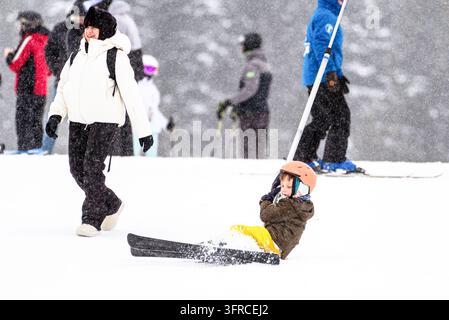 Ruzomberok, Slovaquie – 2 janvier 2026 : Un enfant portant un casque de ski est assis dans la neige après être tombé en utilisant un téléphérique de surface à la station de ski Malino Brdo Banque D'Images