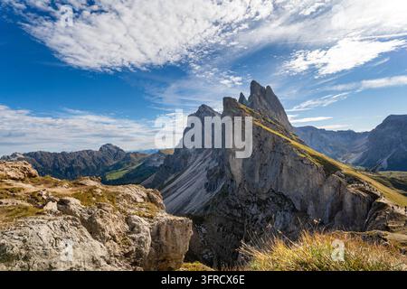 Vue grand angle de la crête emblématique du Seceda dans les Dolomites italiennes avec des falaises abruptes et des pentes herbeuses. Une lumière vive illumine le Banque D'Images