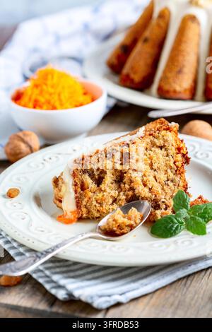 Un morceau de gâteau aux carottes traditionnel avec des raisins secs et des noix est servi dans une assiette avec une branche de menthe, mise au point sélective Banque D'Images