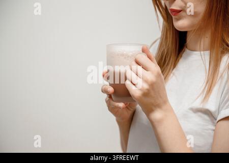 Mains d'une femme tenant une tasse de boisson chaude. Elle sourit et tient une tasse de café dans la main, séparée afin d'inhaler l'arôme du café. Jeune beauté Banque D'Images