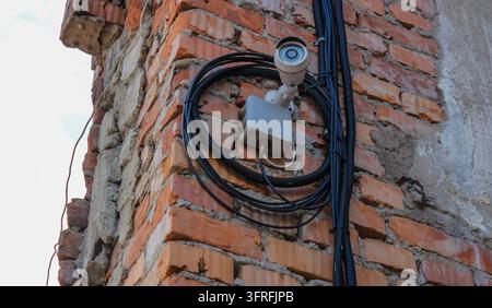 Caméra de surveillance de sécurité et câblage montés sur un vieux mur de briques Banque D'Images