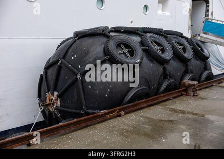 Grand pare-battage en caoutchouc noir maritime fixé le long d'un navire au quai Banque D'Images