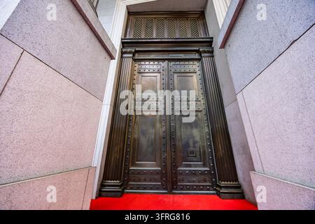 Vue en contre-plongée d'une massive vieille porte en bois historique encastrée dans la façade en pierre d'un bâtiment classique Banque D'Images