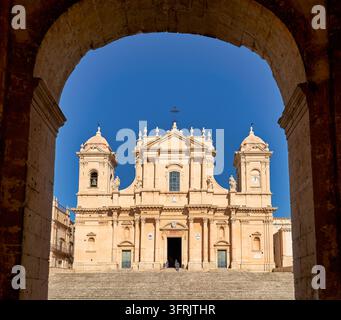 Façade de style baroque tardif de la cathédrale de San Nicolò au-dessus de son grand escalier, vue à travers une arche à Noto, dans le sud-est de la Sicile, en Italie Banque D'Images