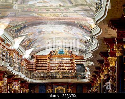 Des fresques peintes au plafond, une galerie en fer forgé doré et des colonnes en bois torsadées encadrent des étagères de vieux livres dans la salle du Klementinum du XVIIIe siècle. Banque D'Images