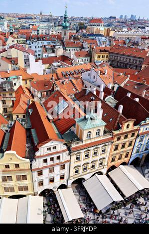 Toits en tuiles rouges et façades en arcades au-dessus des terrasses de cafés en plein air sur la place de la Vieille Ville, Prague, République tchèque, en été Banque D'Images