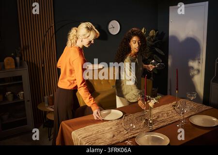 Deux amies préparent une table festive pour une célébration à la maison Banque D'Images