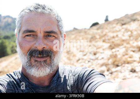 Homme mûr souriant en plein air profitant d'une activité dans la nature Banque D'Images