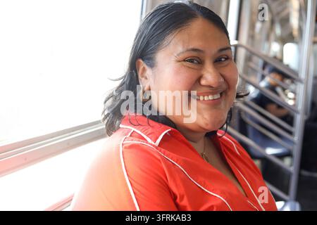 Femme hispanique mature heureuse souriant dans les transports en commun Banque D'Images