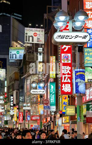 Des foules marchent sous des panneaux illuminés et des enseignes publicitaires sur Shibuya Center Gai, une rue piétonne animée à Tokyo, au Japon, par une soirée de printemps. Banque D'Images
