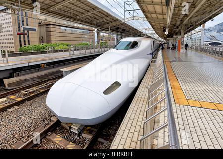 Train à grande vitesse de la série N700 blanc arrêté sur la ligne Tokaido Shinkansen à Kyoto, avec un pavé tactile et quelques passagers sur le quai surélevé Banque D'Images