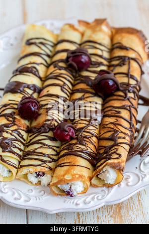 Crêpes avec du fromage frais et de la sauce au chocolat sur une table en bois Banque D'Images