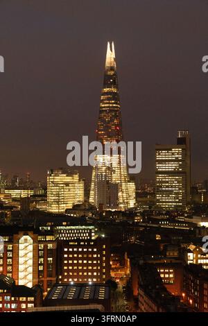 LE GRATTE-CIEL SHARD DE LONDRES PAR UNE NUIT BRUMEUSE, CITY OF LONDON, ARCHIVE REPORTAGE, LONDRES, ANGLETERRE, 2019 : La flèche brillamment éclairée du Shard perce un ciel nocturne sombre et brumeux au-dessus de Londres, entourée par d’autres immeubles de bureaux et résidentiels illuminés. INFO : La City of London, également connue sous le nom de Square Mile, est le cœur historique et le principal district financier mondial de Londres. Fonctionnant sous son propre gouvernement municipal ancien et unique, elle mêle gratte-ciel ultramodernes à des monuments emblématiques anciens. Banque D'Images