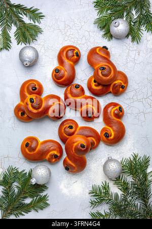 Petits pains au safran suédois, branches de sapin et boules de Noël sur un fond gris craquelé. Vue de dessus, flat lay Banque D'Images