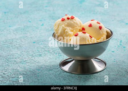 Une glace artisanale avec une belle décoration est servie dans un vase en métal sur un fond turquoise texturé, mise au point sélective Banque D'Images