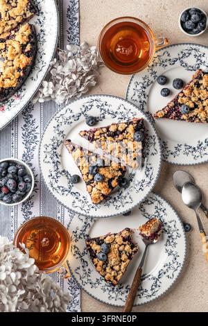 Tarte ou gâteau au crumble d'avoine cuit au four avec des myrtilles fraîches sur des assiettes en céramique servies pour le thé, vue de dessus. Menu, recette. Vertical Banque D'Images