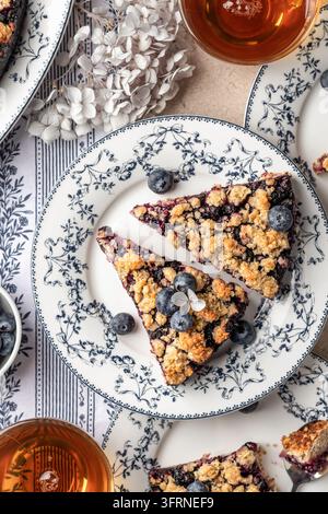 Tarte ou gâteau au crumble d'avoine cuite au four avec une myrtille fraîche sur une assiette en céramique, gros plan servi pour le thé, vue de dessus. Menu, recette. Vertical Banque D'Images