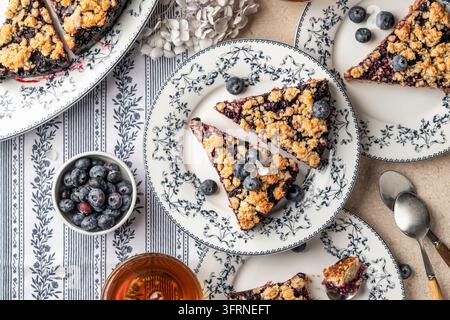 Tarte ou gâteau au crumble d’avoine cuite au four avec des myrtilles fraîches sur des assiettes en céramique servies pour le thé, vue de dessus. Menu, recette. Horizontal Banque D'Images