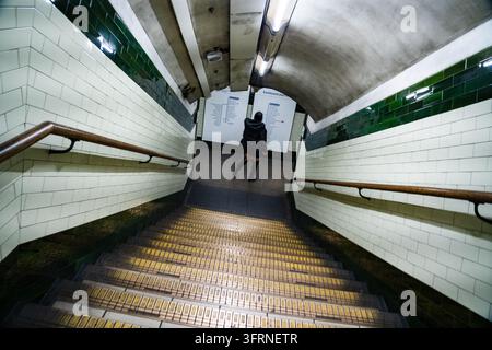 DESCENDRE DANS LE MÉTRO, ARCHIVES DE REPORTAGE DU METRO DE LONDRES, LONDRES, ANGLETERRE, 2019 : Une femme seule, vêtue d’un manteau noir et de bottes, descend une large volée d’escaliers carrelés vers une station de métro. INFO : Le métro de Londres, affectueusement appelé « le Tube », est le plus ancien réseau ferroviaire souterrain du monde, ouvrant sa première ligne en 1863. Avec 11 lignes sur 272 stations, ce réseau emblématique transporte quotidiennement des millions de navetteurs et de visiteurs. Banque D'Images