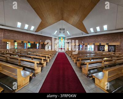 JOHANNESBURG - 25 NOV 2023 : Église avec un tapis rouge menant à l'autel. Les bancs sont vides. Il y a des vitraux sur les murs à Johannesburg en Afrique du Sud Banque D'Images