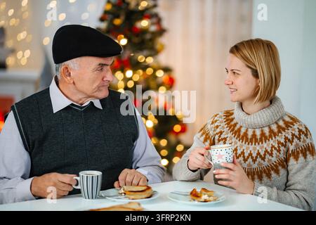 Grand-père et fille partageant une conversation pendant le petit-déjeuner de Noël Banque D'Images